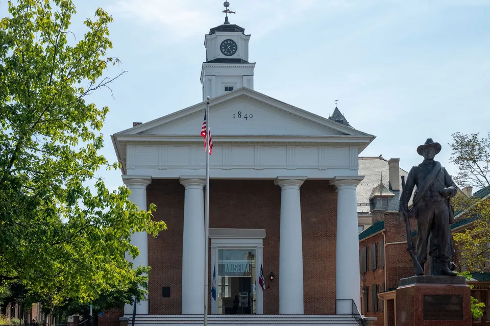 Historic courthouse facade with statue and American flag in daylight.